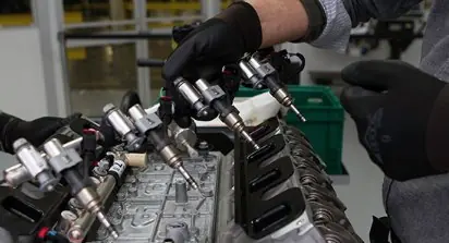 Gasoline injector tips caked with carbon deposits versus a clean spray pattern